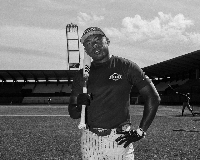 Posed black and white photo of a baseball player resting a bat on his shoulder.